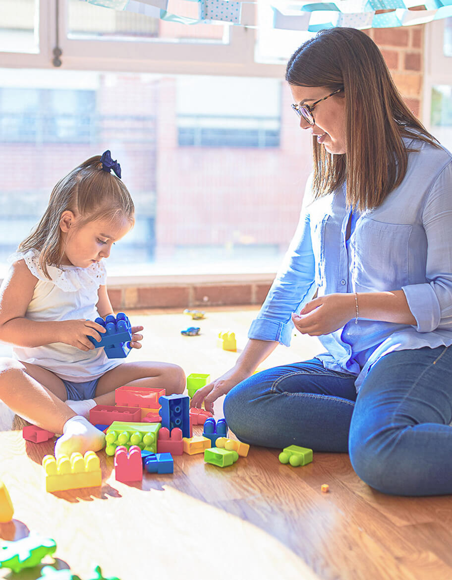 Kind und Betreuerin spielen mit Bauklötzen